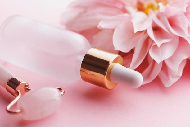 Facial serums for every skin type: A close-up view of a skincare serum bottle and a jade roller, highlighting essential beauty tools for a glowing complexion.